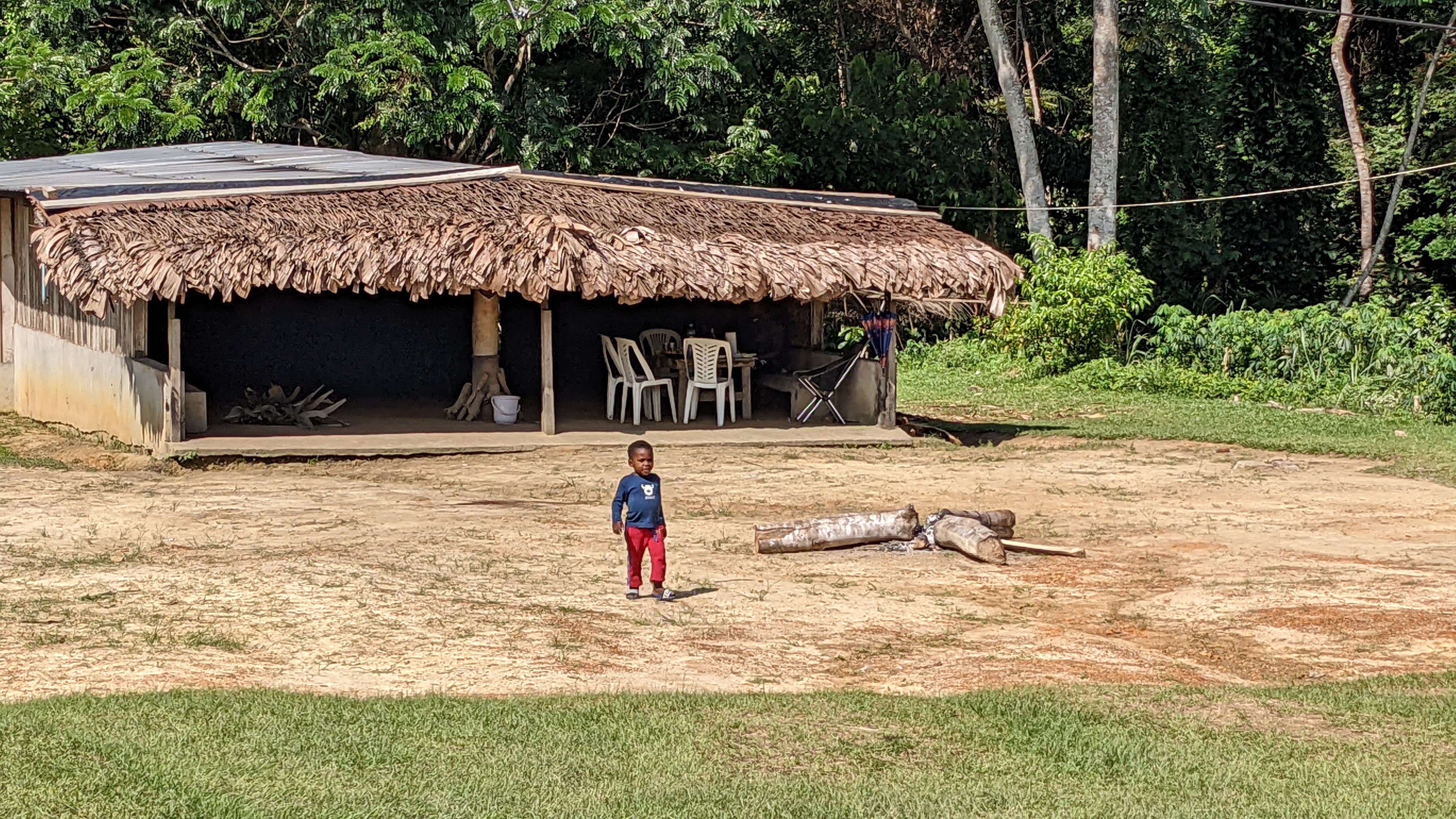 Child outside a traditional thatched-roof village building in Gabon